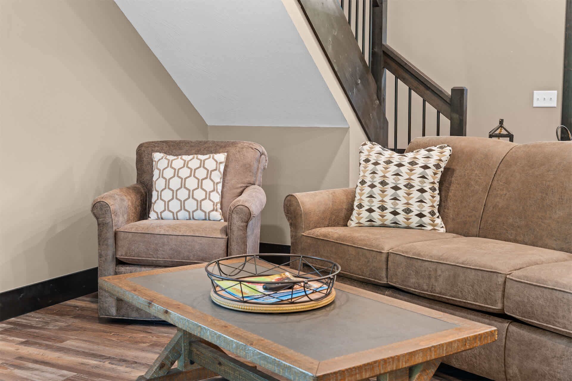 A living room with a brown leather sofa, a matching armchair, and a coffee table with a colorful coaster.