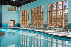 A swimming pool with clear blue water, surrounded by large windows and lounge chairs. - 8 Tall Oaks - Tall Timbers Escape (Hollister)