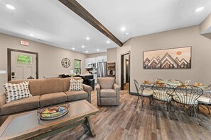 A modern living room with a sofa, armchair, and dining table. - 8 Tall Oaks - Tall Timbers Escape (Hollister)