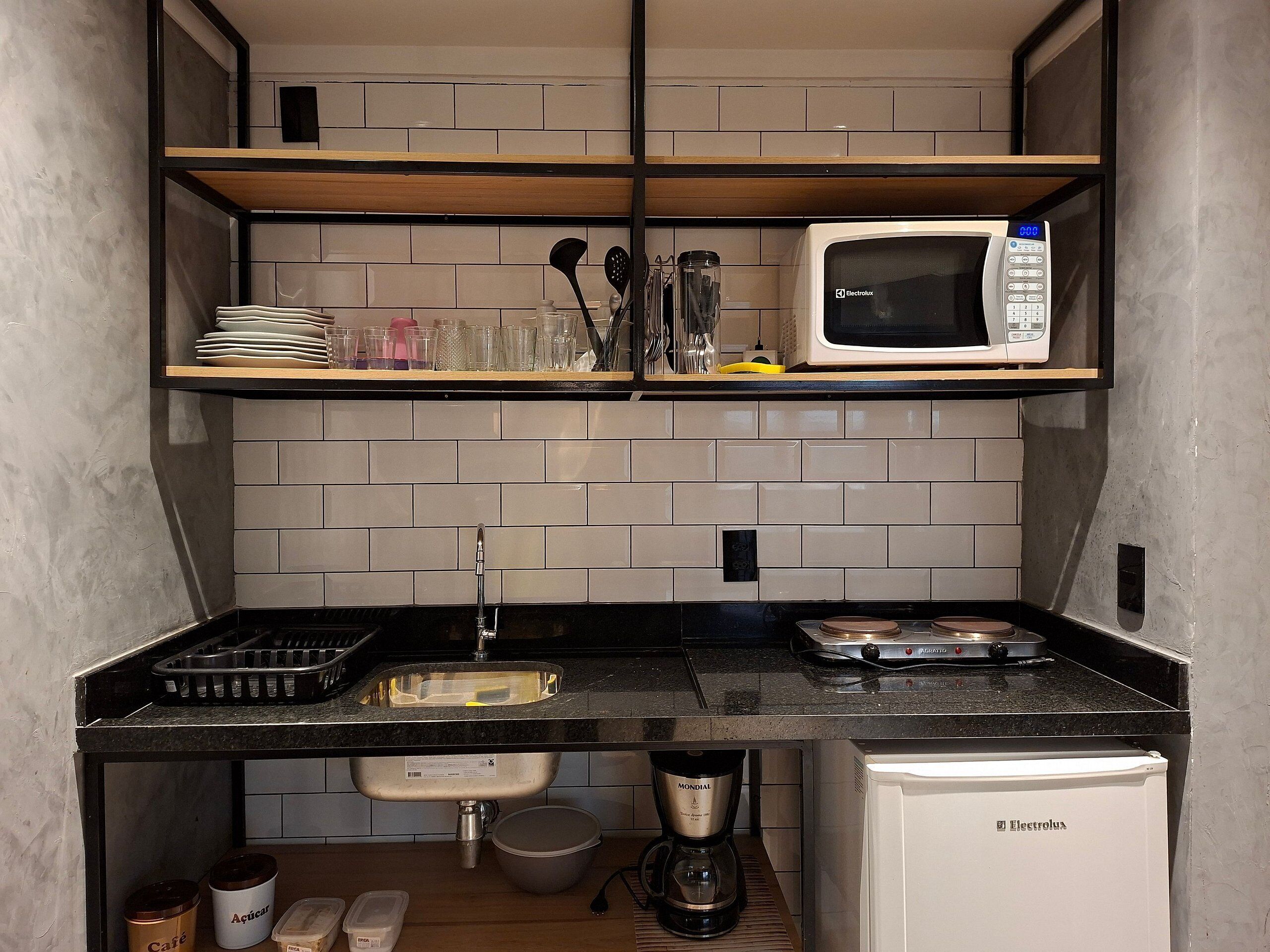 Una cocina compacta con microondas, cafetera y un refrigerador pequeño.