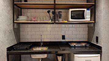 Una cocina compacta con microondas, cafetera y un refrigerador pequeño.