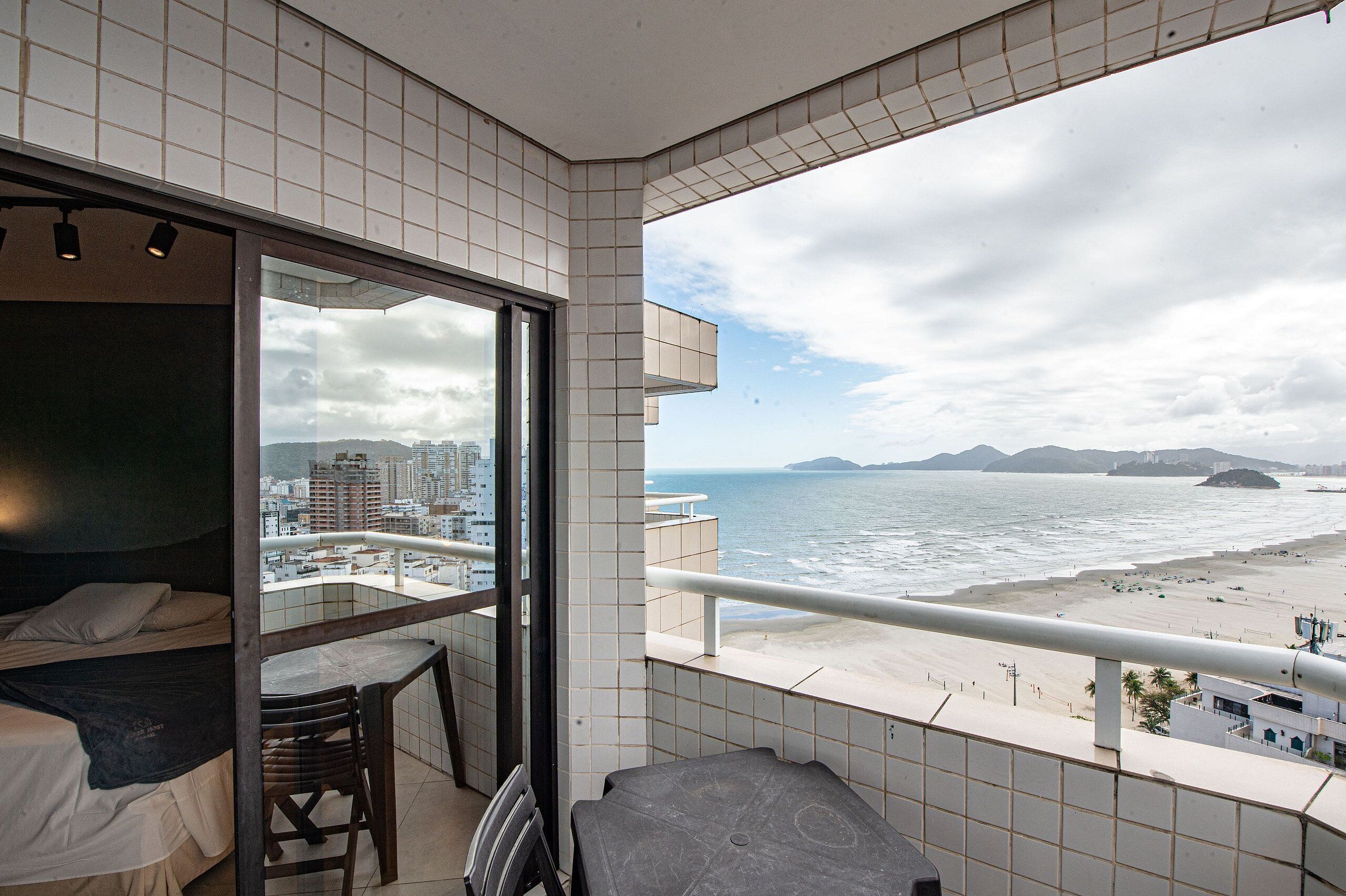 Un balcón con vista a la ciudad, una cama y una mesa.