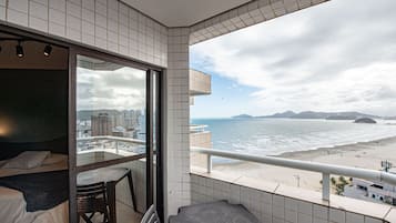 Un balcón con vista a la ciudad, una cama y una mesa.