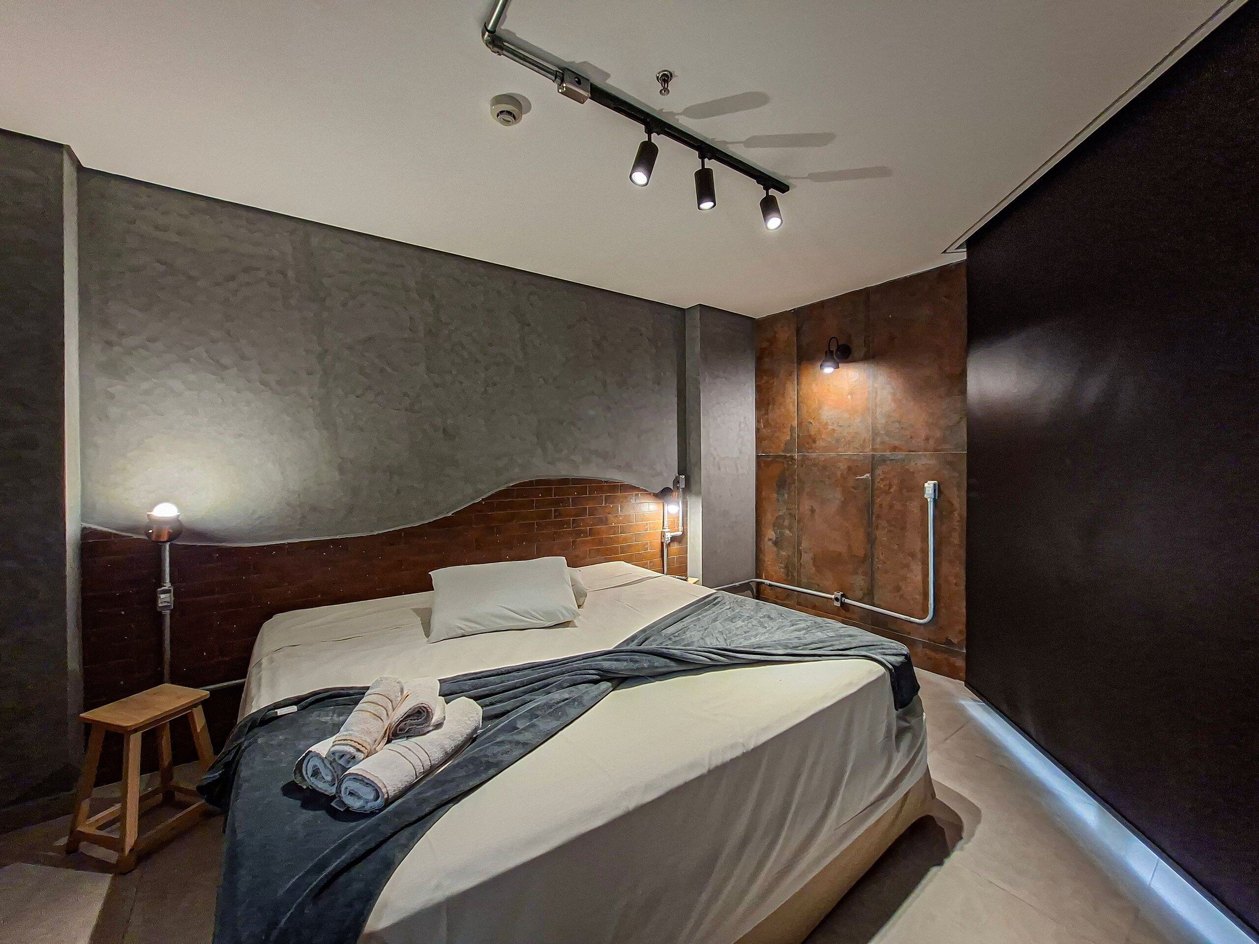 Un dormitorio moderno con una cama grande, cabecera de madera, mesita de noche y ventilador de techo.