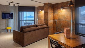 Un salon moderne avec un canapé, une table à manger en bois et un téléviseur fixé au mur.