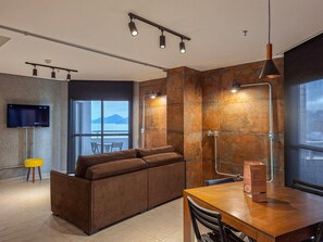 Una sala de estar moderna con un sofá, una mesa de comedor de madera y un televisor montado en la pared.