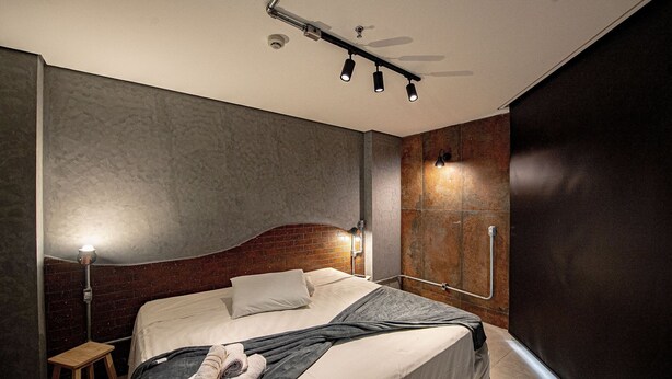Une chambre moderne avec un lit, une table de chevet et un luminaire fixé au mur.