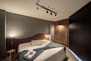 Un dormitorio moderno con cama, mesita de noche y lámpara fijada a la pared.