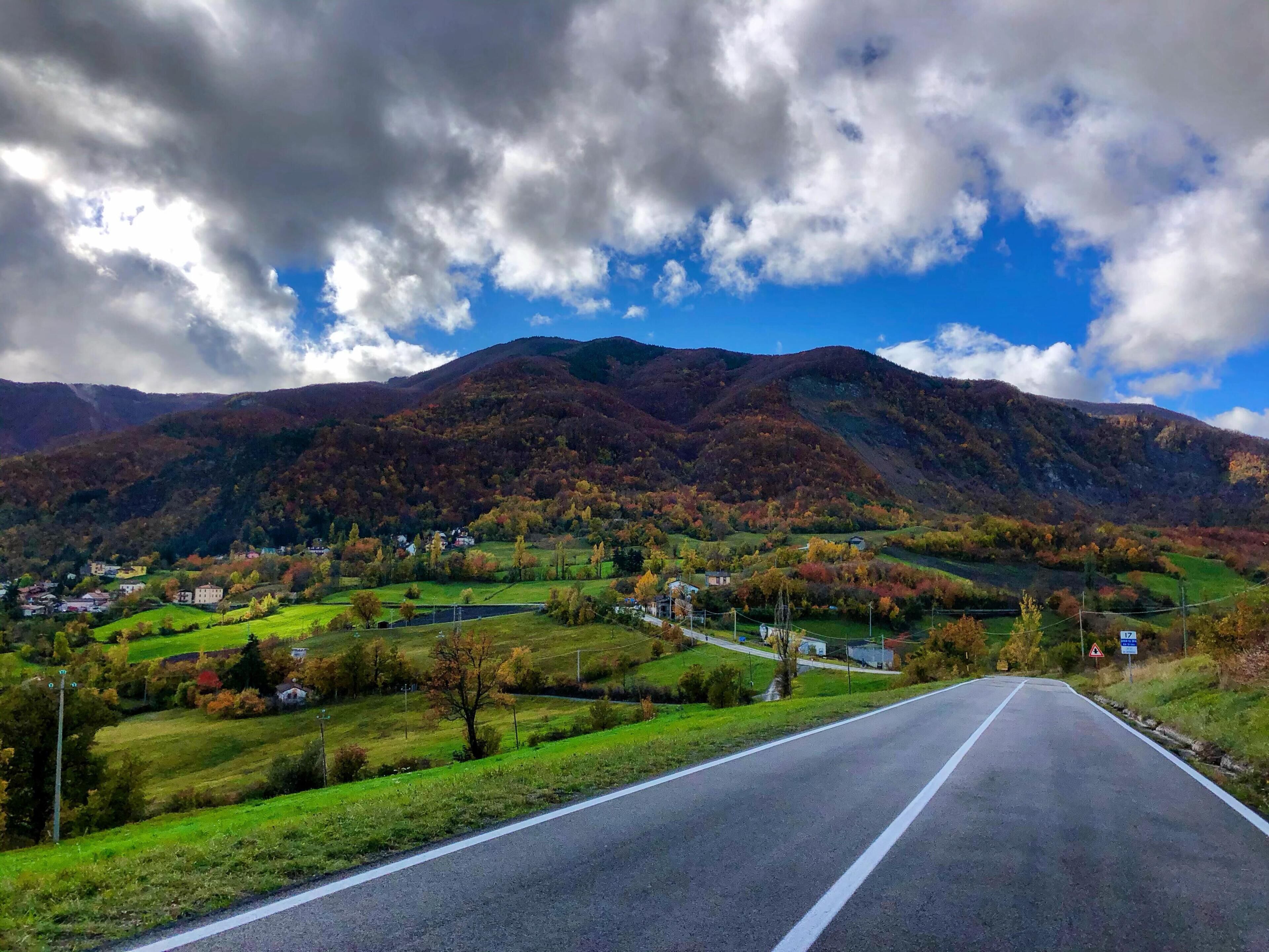 A road leading through a valley with houses and mountains in the background.