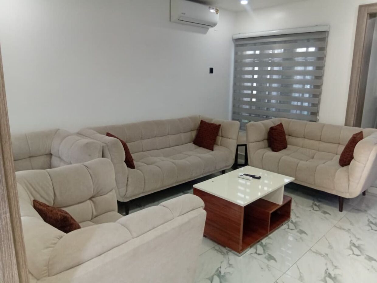 A living room with a sofa set, a coffee table, and a window with blinds.