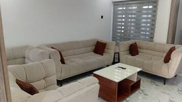 A living room with a sofa set, a coffee table, and a window with blinds.