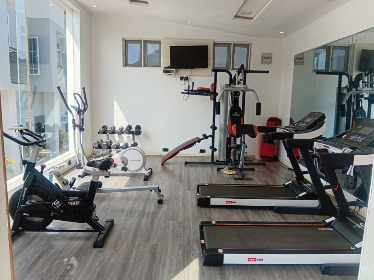 Een sportschool met loopbanden, een hometrainer en krachttoestellen.
