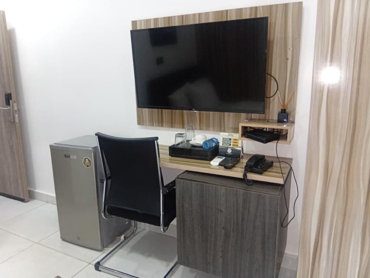 Een klein kantoor met een bureau, stoel en een flatscreen aan de muur.