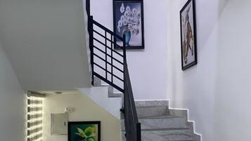 A staircase with a black handrail and white walls, leading to an upper floor.
