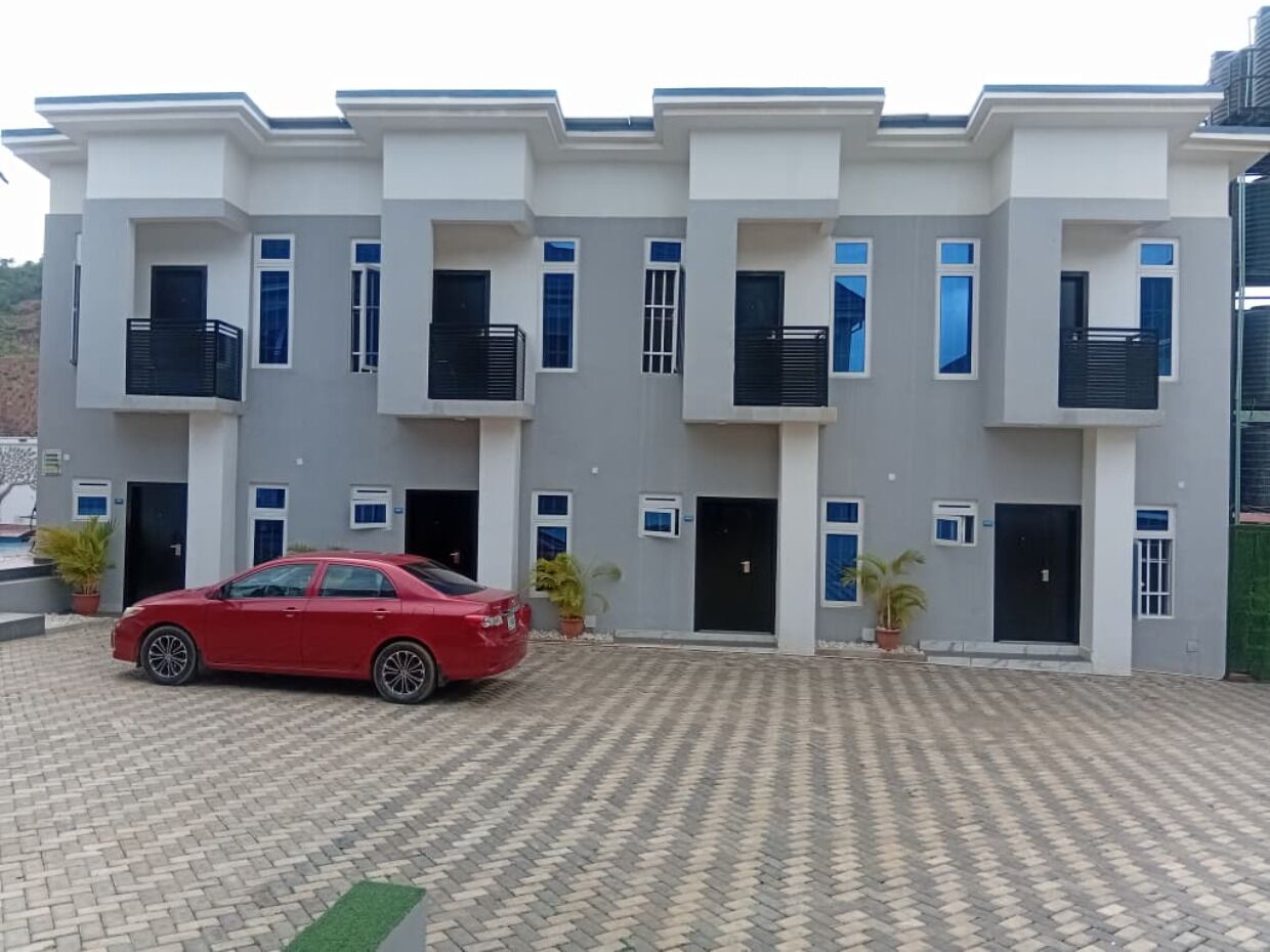Um edifício residencial com vários andares e um carro vermelho estacionado na frente.
