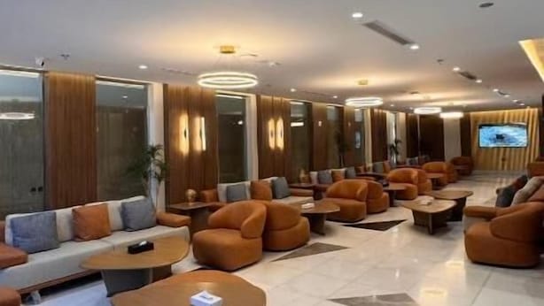 Un hall d’entrée spacieux doté de plusieurs espaces de détente, notamment des canapés et des fauteuils, ainsi qu’un écran de télévision.