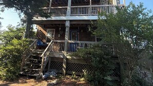 A two-story wooden cabin with a balcony, surrounded by trees.