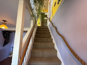 A staircase with a wooden handrail, carpeted steps, and a wall-mounted rope handrail. - Spacious 5-bedroom house in fantastic Ocracoke with AC (Ocracoke)