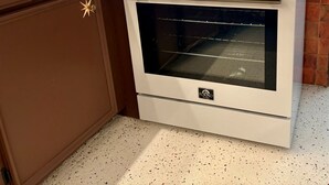 A kitchen with a white stove, a brown cabinet, and a backsplash with a geometric pattern.