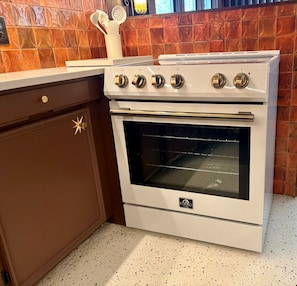 A kitchen with a white stove, a brown cabinet, and a backsplash with a geometric pattern.