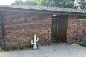 A brick building with a door labeled '701' and a cactus sculpture outside.