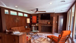 A living room with a fireplace, wooden furniture, and a television.