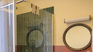 Une salle de bain moderne avec une douche à parois de verre, un lavabo blanc et un meuble-lavabo en bois agrémenté de serviettes.
