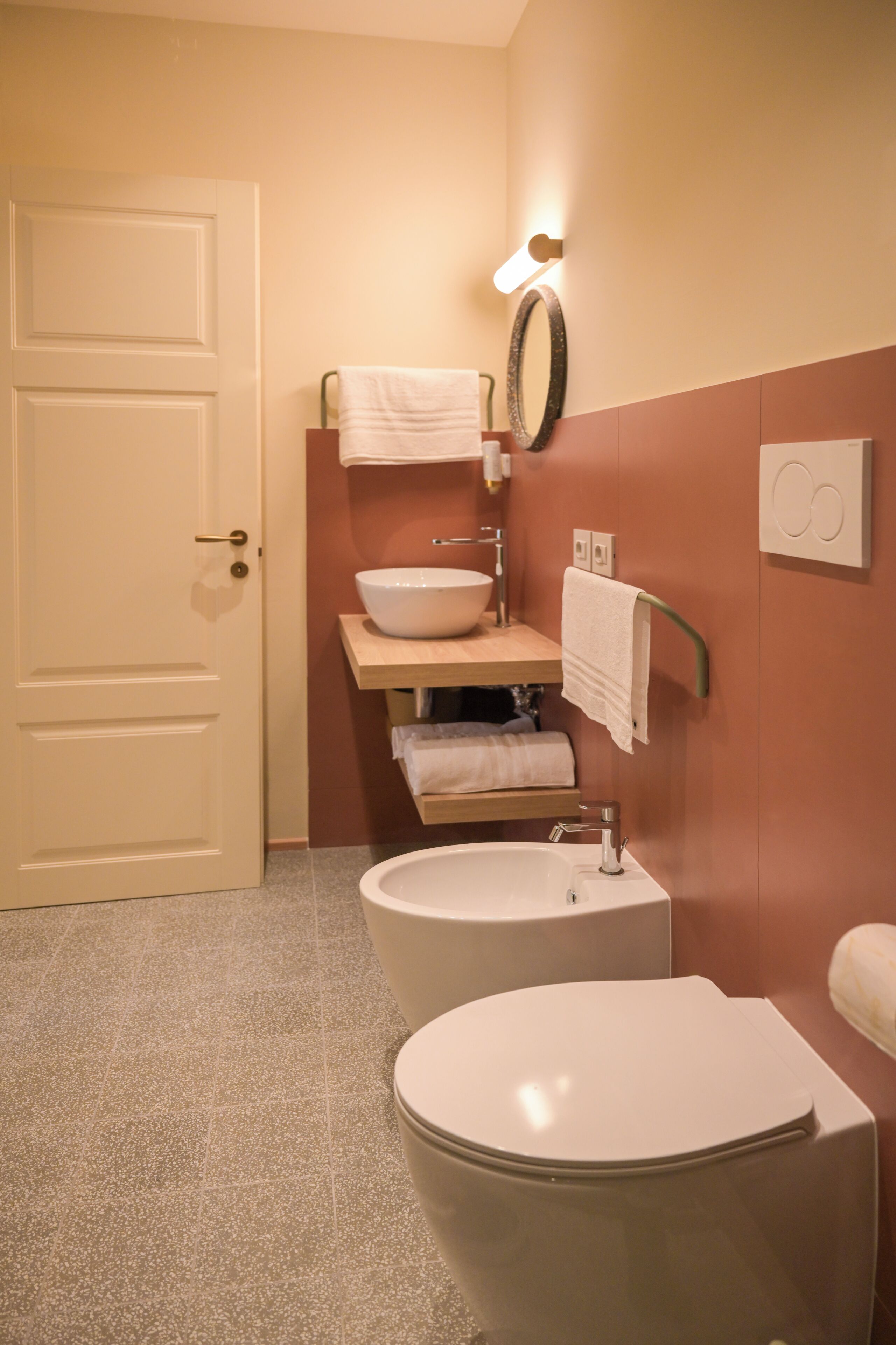 Een badkamer met toilet, wastafel en spiegel.