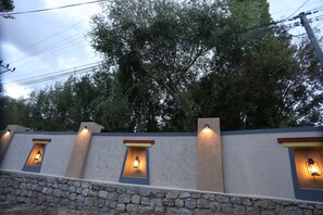 Mur de pedra amb llums integrades i un arbre al fons.