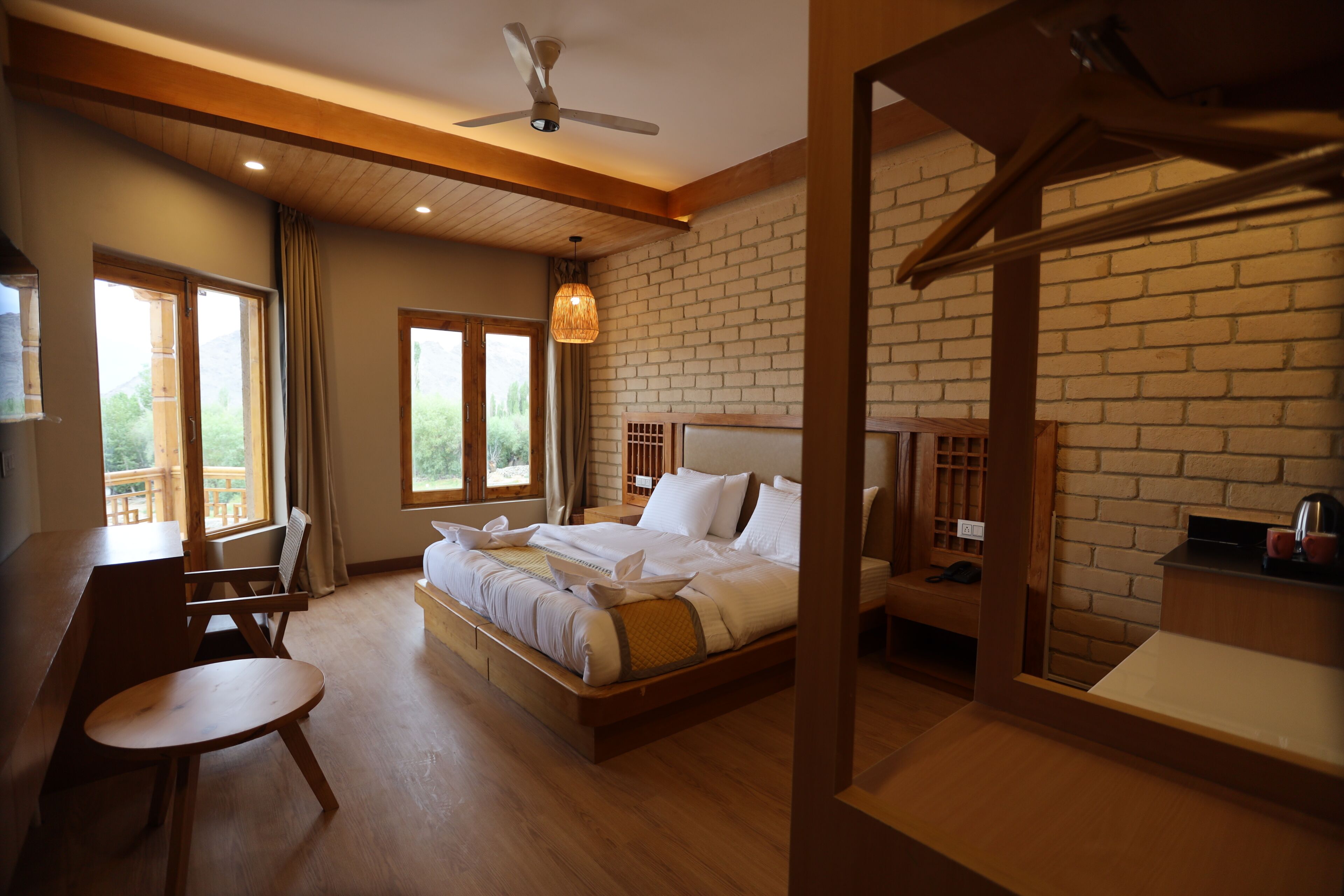 Habitación de hotel con una cama grande, un escritorio, una silla y vistas al exterior.
