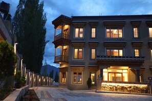 A multi-story building with a balcony and multiple windows, surrounded by trees and a paved area. - The Grand View Ladakh (Leh)