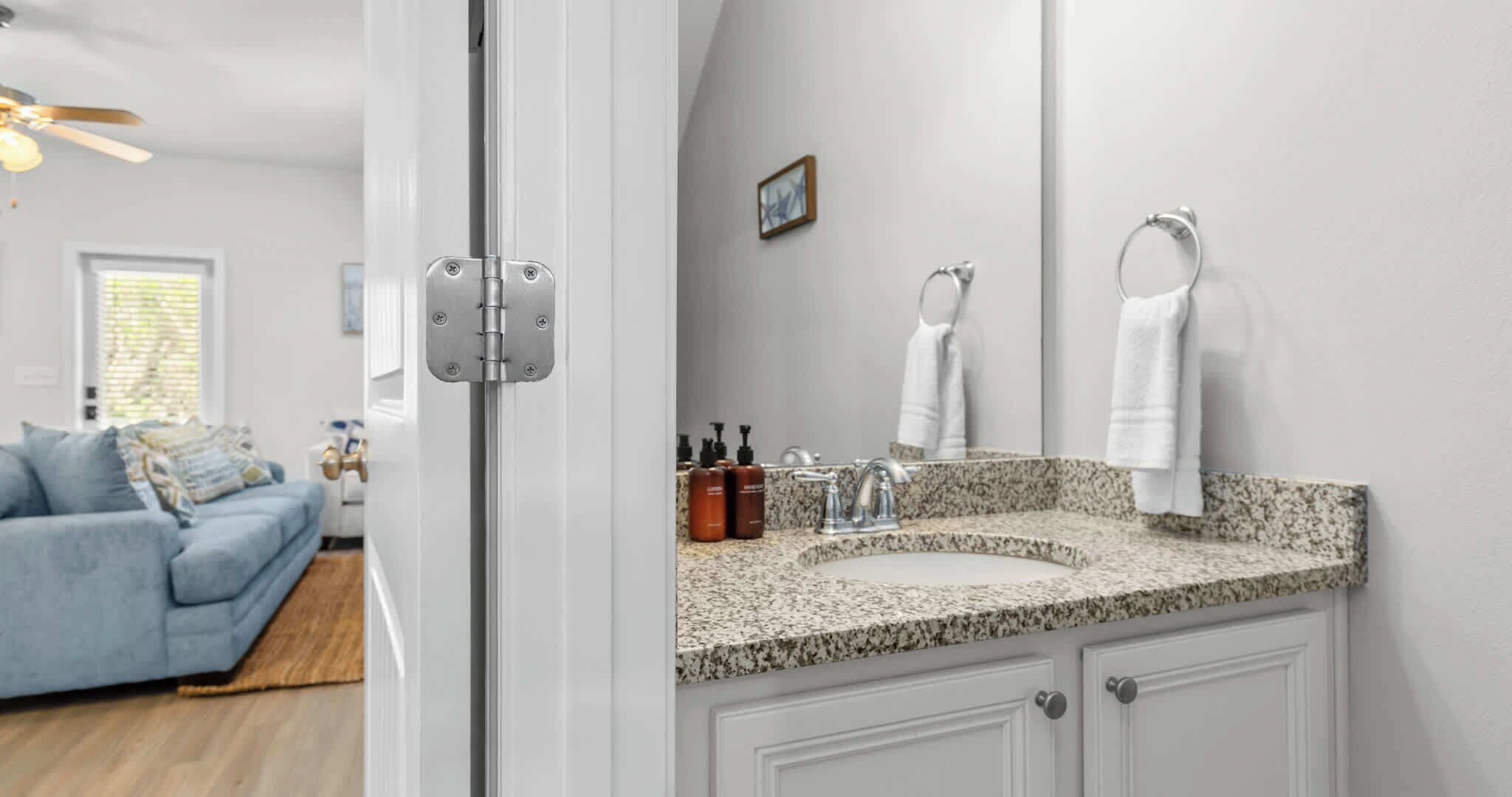 A bathroom with a granite countertop, a sink, a mirror, and a towel rack.