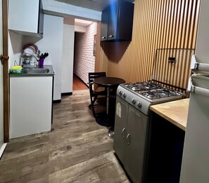 A compact kitchen with a gas stove, a sink, and a dining area with a chair. - Chapinero Apartment, El Campín Stadium, and Movistar Arena. (Bogotá)