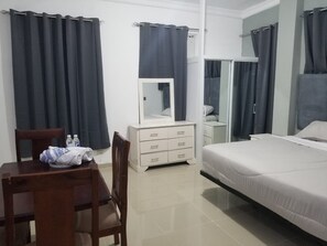 Habitación de hotel con una cama, cómoda, espejo y una mesa con toalla y botellas.