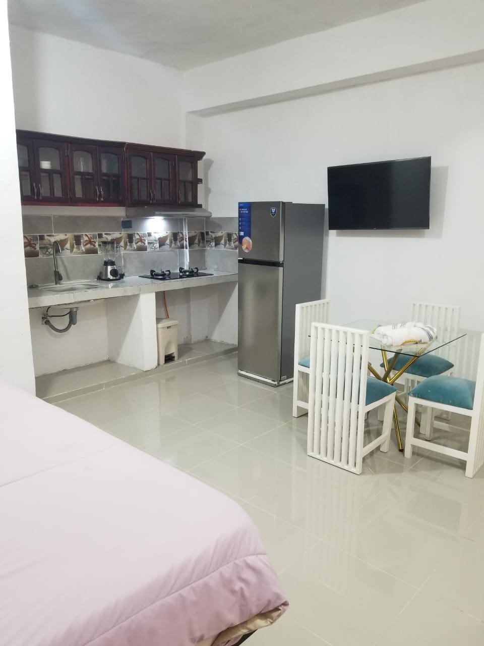 Une chambre d’hôtel compacte comprenant un coin cuisine, un lit, une télévision et un petit espace repas.