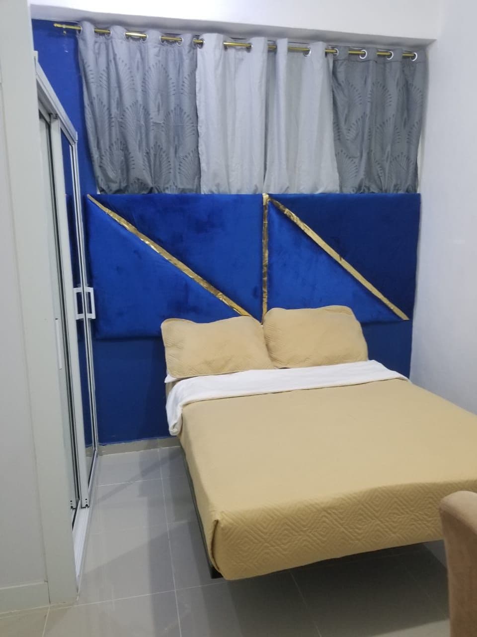 A bedroom with a bed, curtains, and a blue headboard.