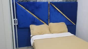 A bedroom with a bed, curtains, and a blue headboard.