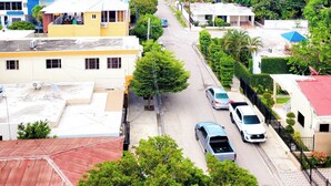 A residential street with houses, cars, and greenery. - Yireh Hotel Grand Suites (San Juan de la Maguana)