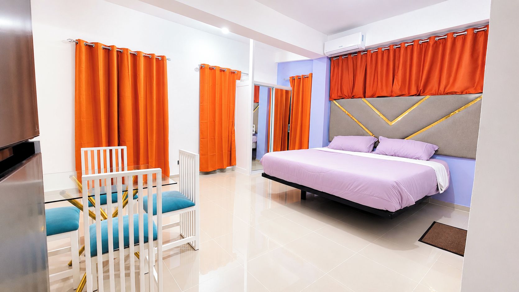 A modern bedroom with a bed, a chair, and orange curtains.