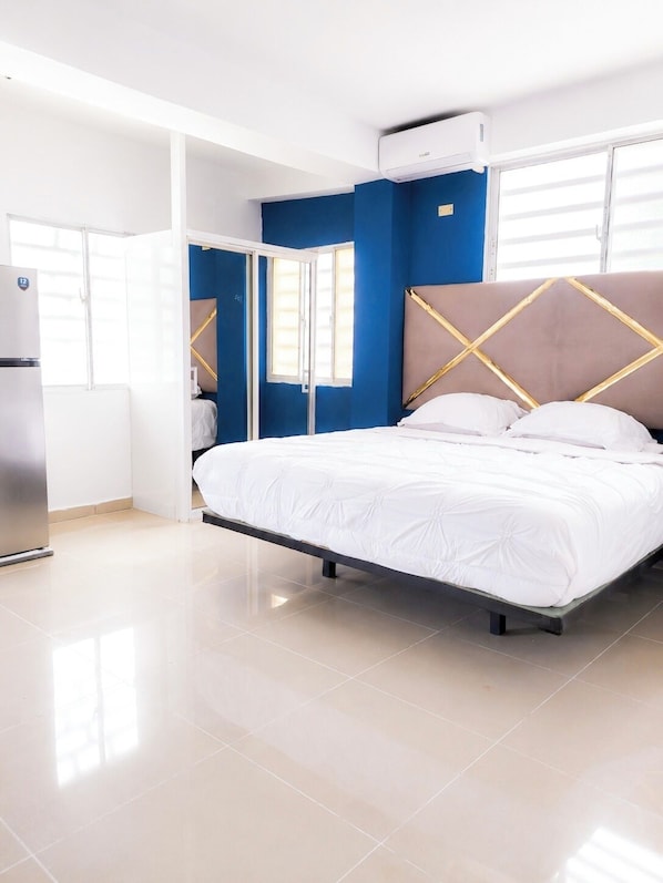 A modern bedroom with a bed, a wardrobe, and an air conditioning unit.