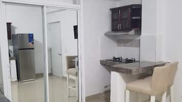 A compact living space with a kitchenette, a sliding glass door leading to another room, and a small dining area with a chair.
