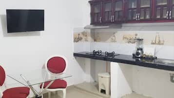 Une cuisine avec un plan de travail noir, des placards blancs et une chaise rouge.