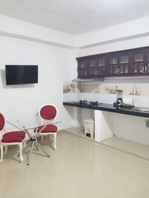 A kitchen with a black countertop, white cabinets, and a red chair.