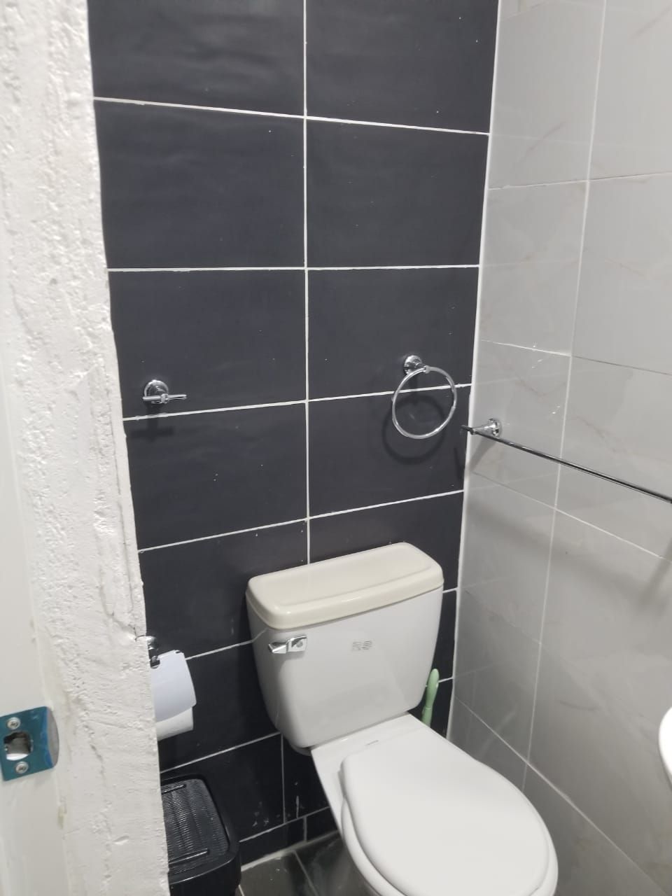 Une salle de bain avec des toilettes, un porte-serviettes et un rouleau de papier toilette accroché au mur.