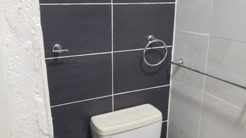 Une salle de bain avec des toilettes, un porte-serviettes et un rouleau de papier toilette accroché au mur.