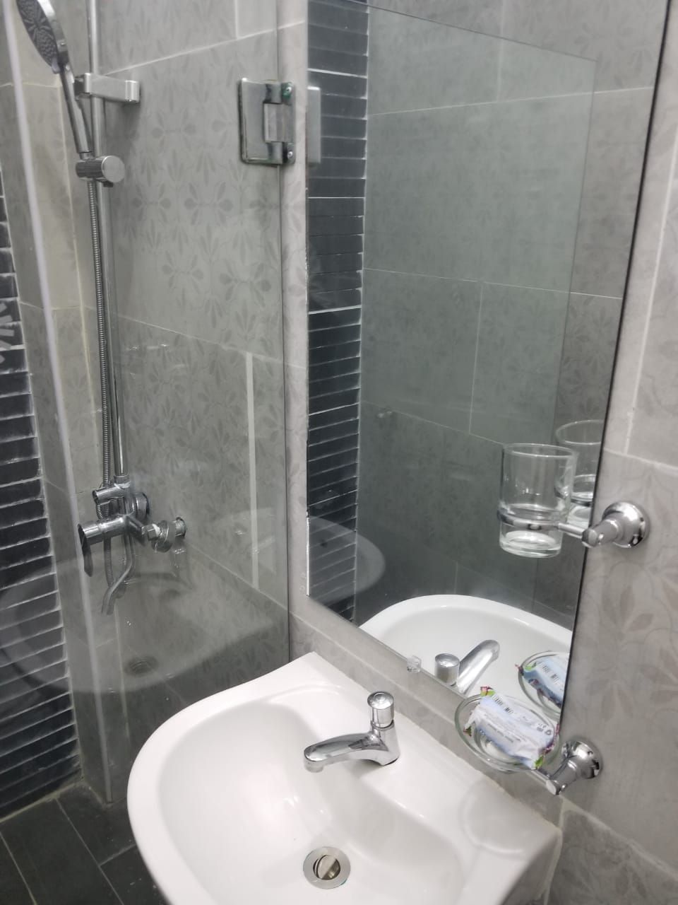 Une salle de bain avec une douche à parois de verre, un lavabo blanc et un miroir.