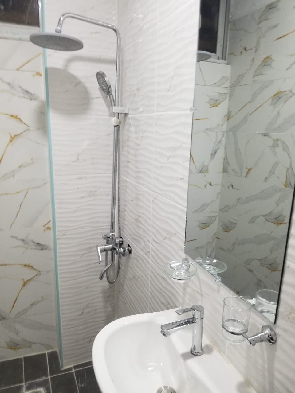 Un baño con cabina de ducha de vidrio, un lavabo y un espejo.