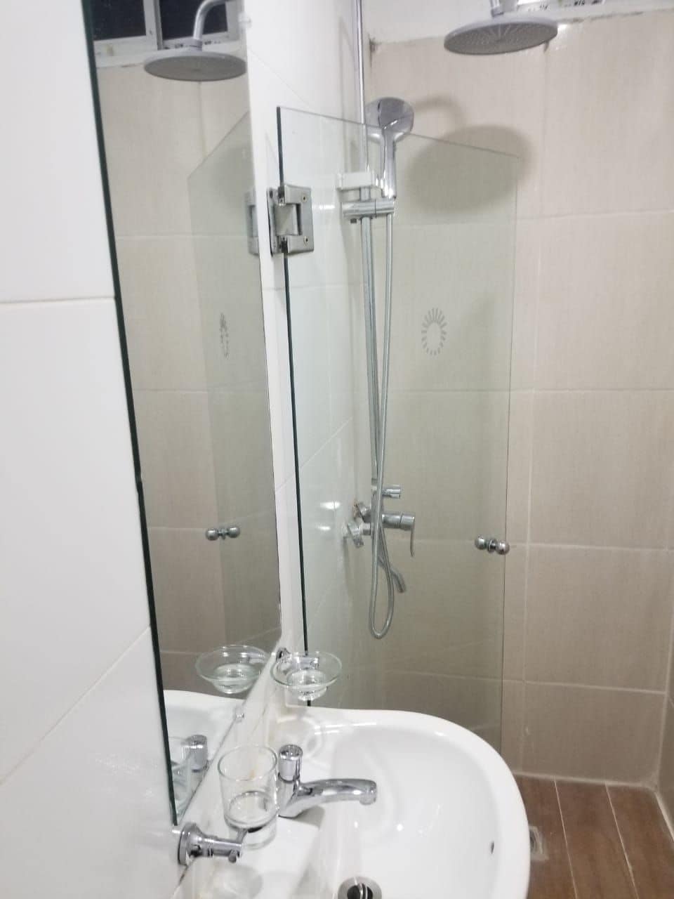 Ein Badezimmer mit einer Duschkabine, einem weißen Waschbecken und einem Spiegel.