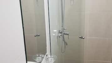 Ein Badezimmer mit einer Duschkabine, einem weißen Waschbecken und einem Spiegel.