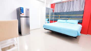 A modern hotel room with a bed, a seating area, and a refrigerator.